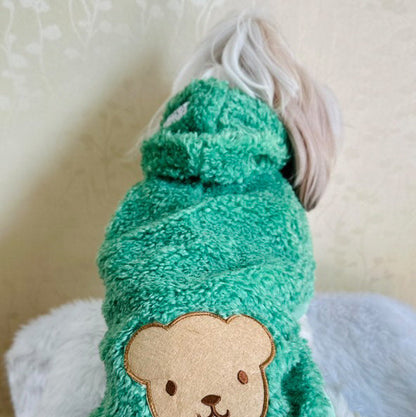 Green plush toy with a bear face on a white surface